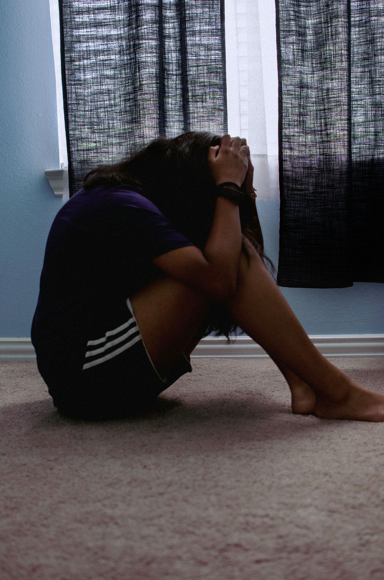 a woman sitting on the floor with her head in her hands